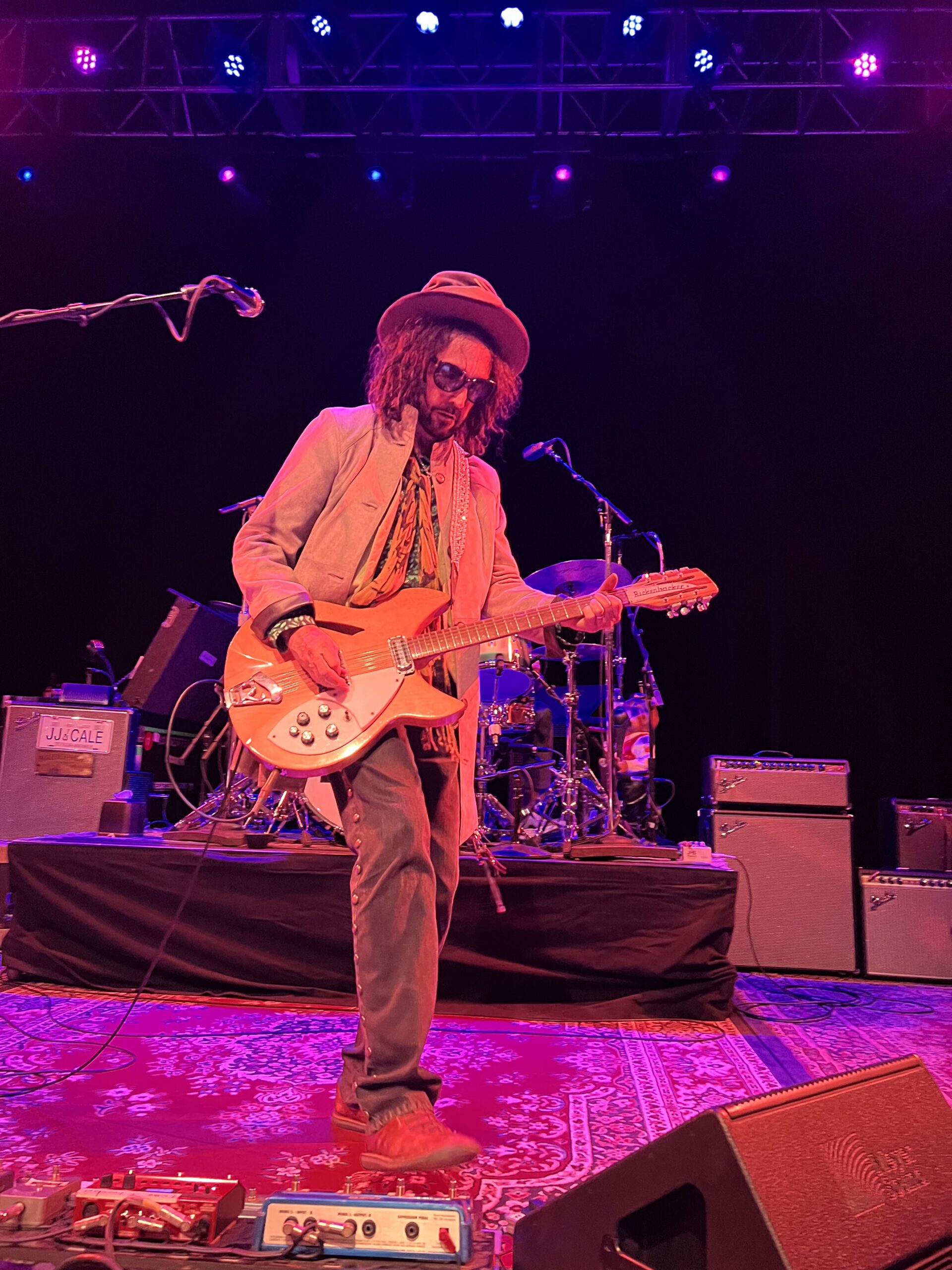 Mike Campbell playing a white Gibson Thunderbird guitar at the front of the stage at the Gothic Theater in Denver.