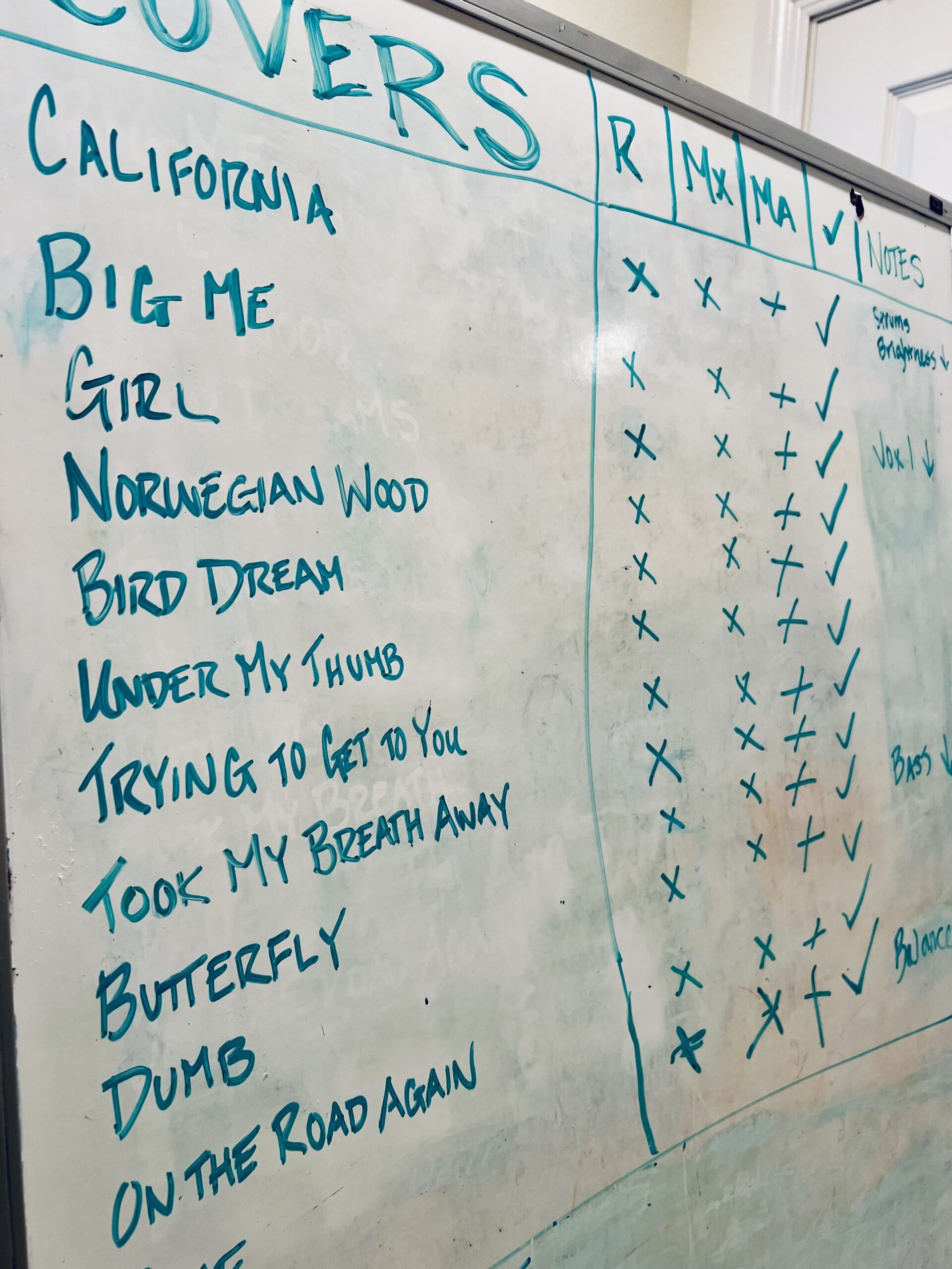 Marker whiteboard with a handwritten track list of cover songs and recording notes.