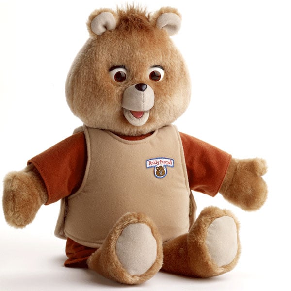 Light brown plush bear wearing a tan shirt with read sleeves and arms wide open as if asking for a big warm hug.